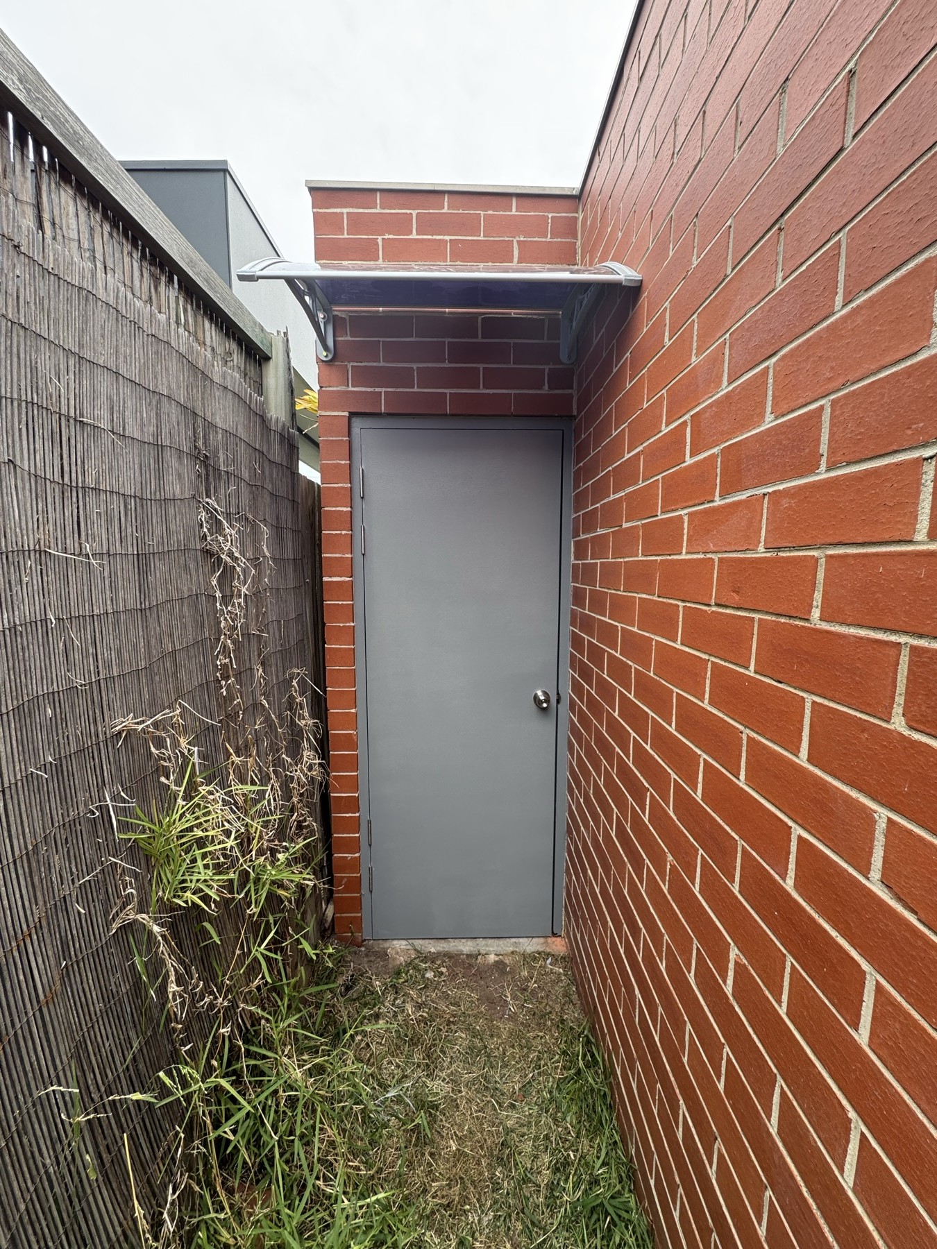 Exterior doorway in a narrow passage beside a brick wall