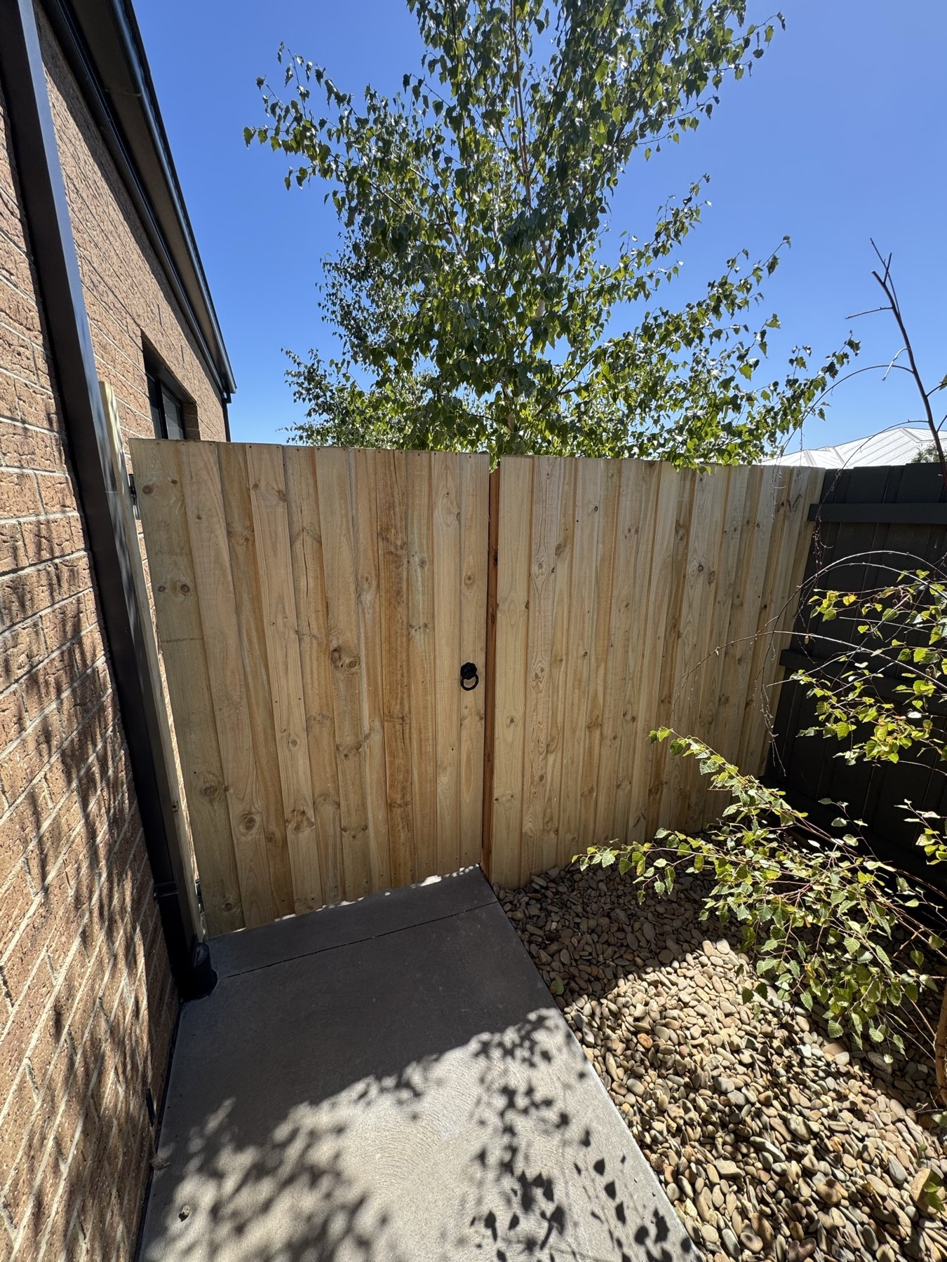 Timber paling boundary fence beside a brick house