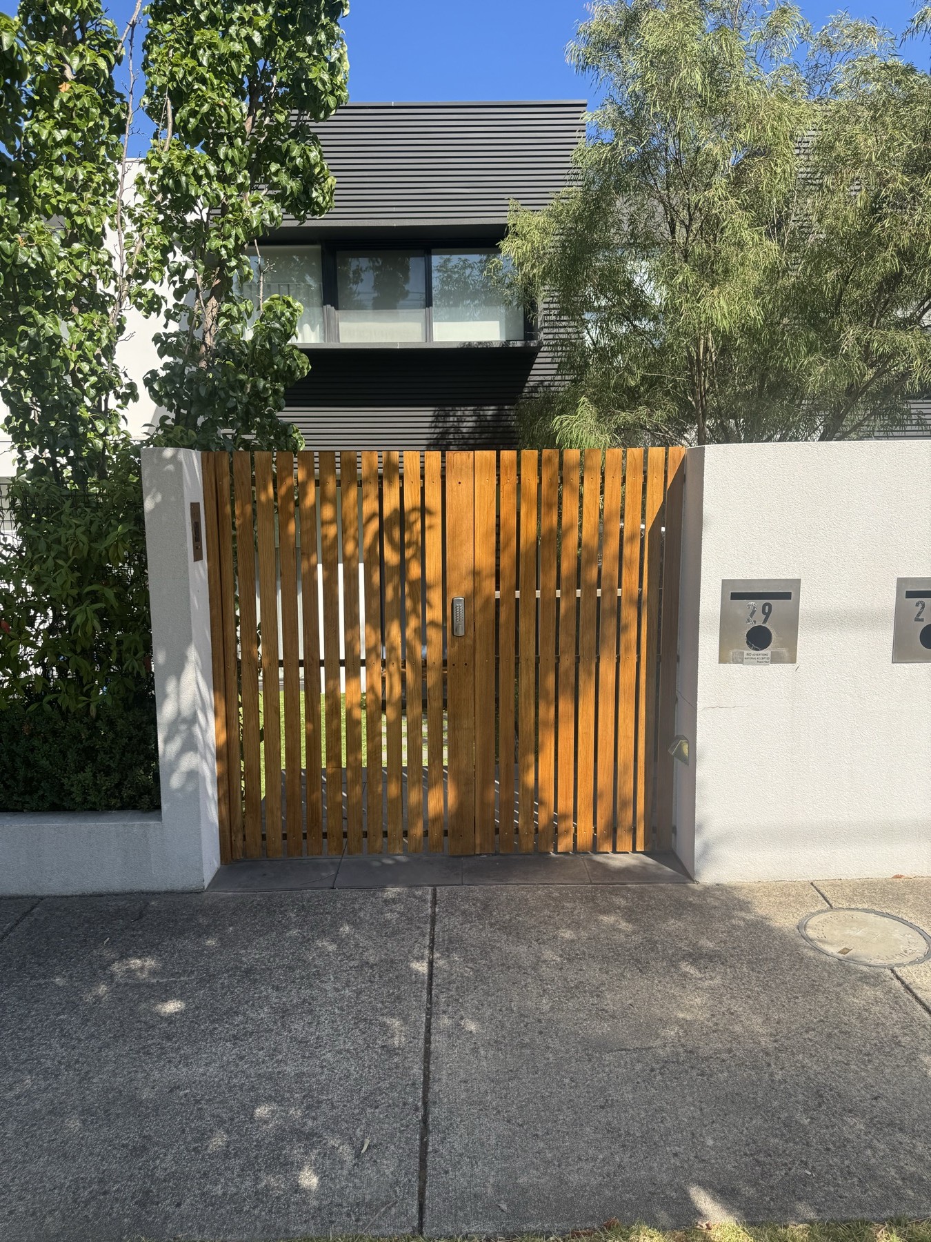 Timber driveway gate set into a rendered front boundary