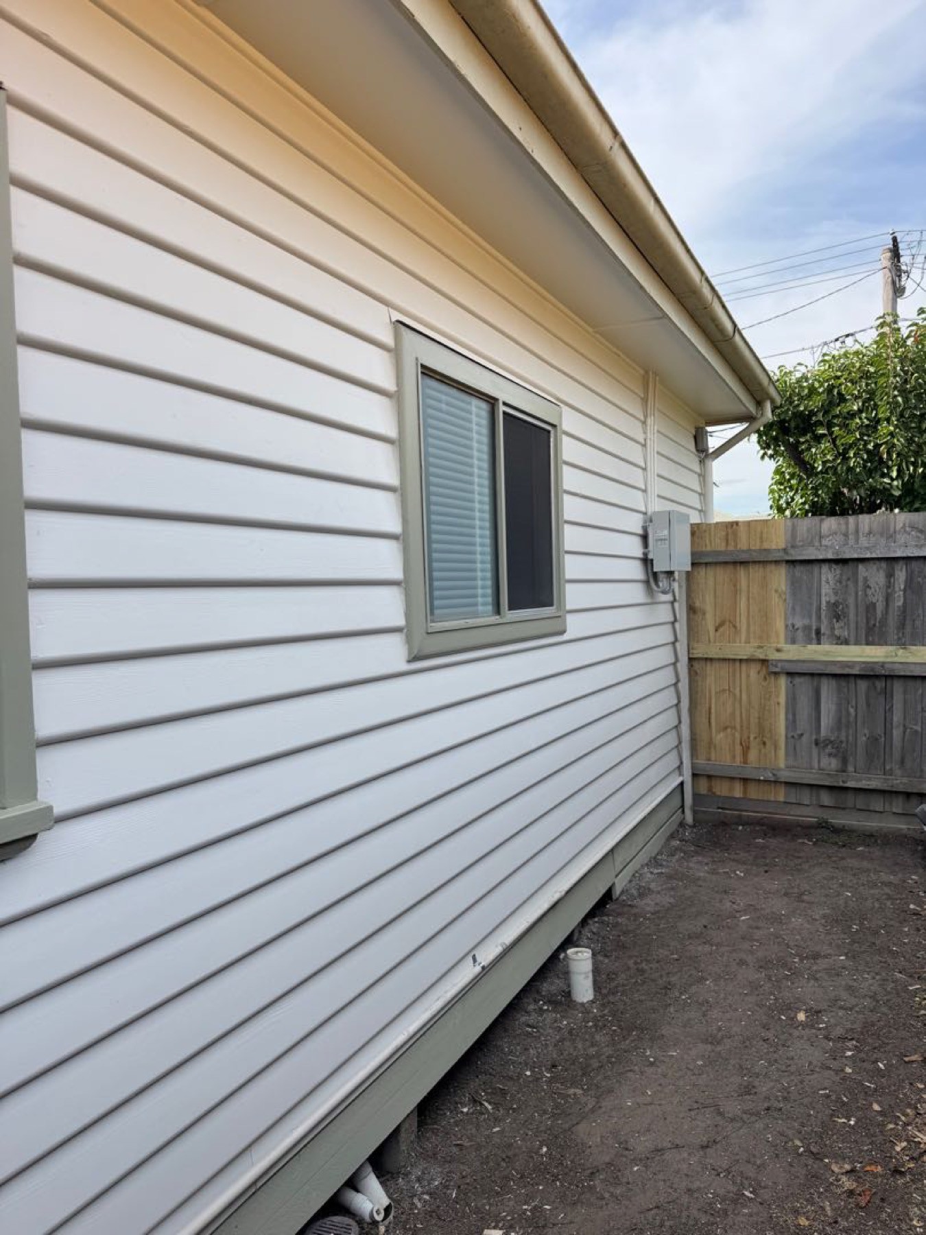 White weatherboard exterior beside a timber fence